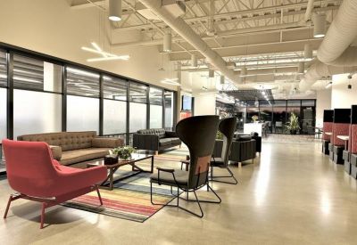 Modern lounge area with a red armchair, designer lighting, and vibrant striped rug.