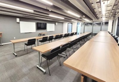 Large training room with rows of long tables and black chairs facing a presentation wall.