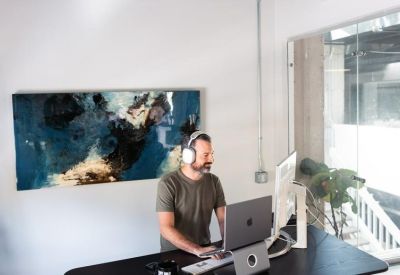 A height-adjustable standing desk with dual monitors and abstract wall art.
