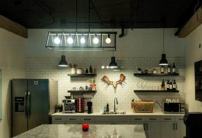 Modern office kitchen with a subway tile backsplash, open shelving, and a large marble island.