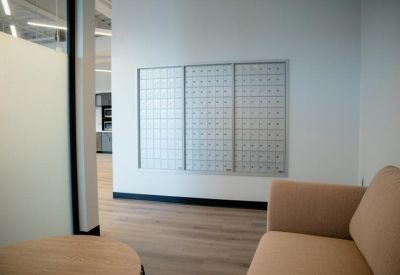 Interior waiting area with a comfortable tan couch and wall-mounted mailbox bank.