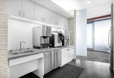 Clean communal kitchen area with white cabinetry and stainless steel appliances.