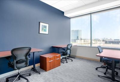 Bright private office with three desks and large windows overlooking the city.