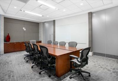 Large professional conference room with a long wood table and grey mesh chairs.