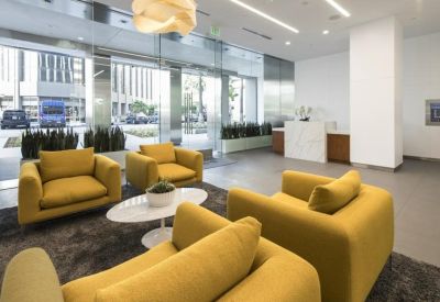Bright lobby with yellow armchairs and a marble reception desk.