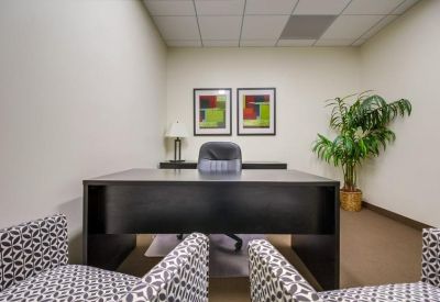 Internal office suite with a dark wood desk and patterned armchairs.