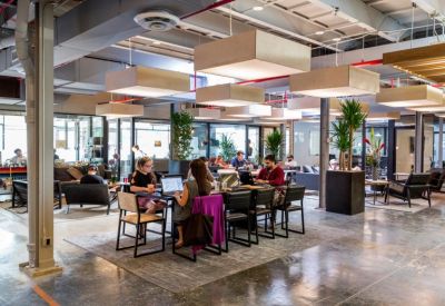 Spacious communal coworking area with large rectangular pendant lights and a variety of seating.