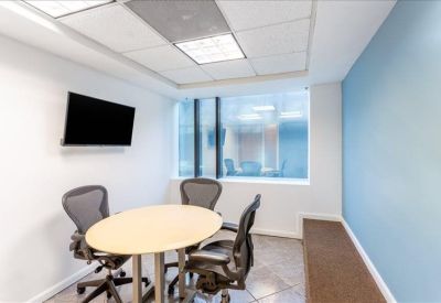 Modern meeting room with a round table, television screen, and blue feature wall.