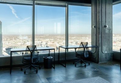Two minimal black desks facing large windows with an expansive city and stadium view.