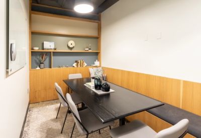 Private meeting room with a dark wooden table, grey chairs, and built-in wooden shelving.