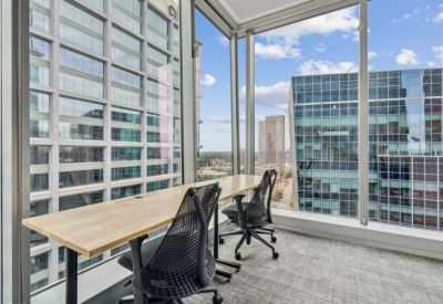 Modern coworking workspace with two desks facing large windows overlooking Charlotte high-rises.