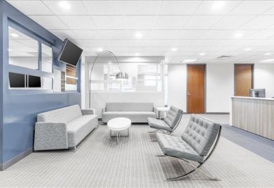 Contemporary lounge area with grey sofas and mid-century modern chairs against a blue accent wall.