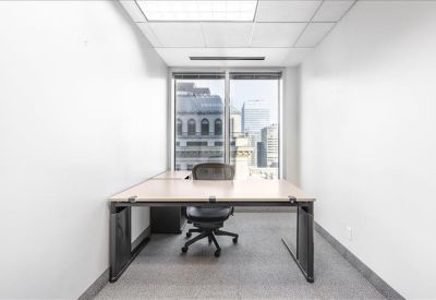 Private office suite with a wooden desk and city views through large windows.
