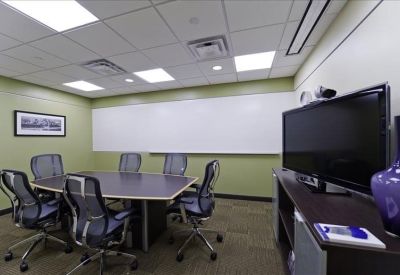 Small conference room with a wooden table, ergonomic chairs, and a large monitor.