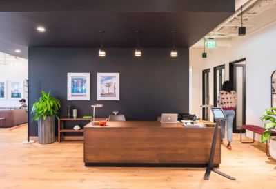 Reception area featuring a dark wood front desk, black feature wall, and indoor plants.