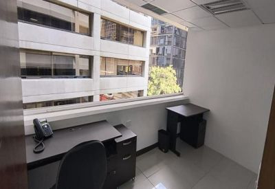 Private office suite with a large window overlooking adjacent city buildings.
