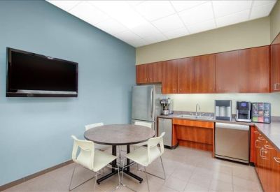 Kitchen and breakout area with wooden cabinetry, stainless steel appliances, and a wall-mounted TV.