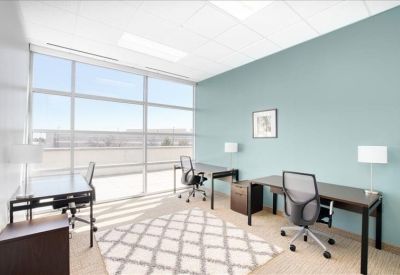Bright three-person office suite with light blue walls and a patterned rug.