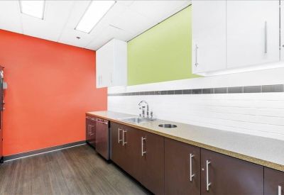 Bright breakroom kitchen with brown cabinetry, orange and lime green walls, and ample counter space.