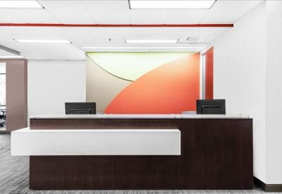 Reception desk with a dark wood finish and a modern orange-toned wall graphic.