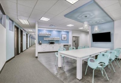 Bright communal kitchen and dining area with blue accent walls and modern light fixtures.
