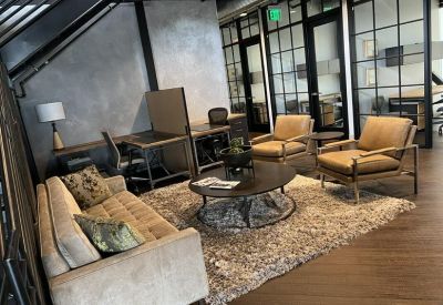 Lounge area with a tan sofa, leather armchairs, and a round coffee table on a shag rug.