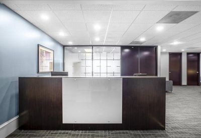 Dark wood and white reception desk in a bright, minimalist lobby.