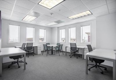 Spacious open-plan workspace with multiple white desks and natural light.