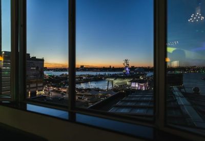View of city skyline and waterfront during sunset from a window.