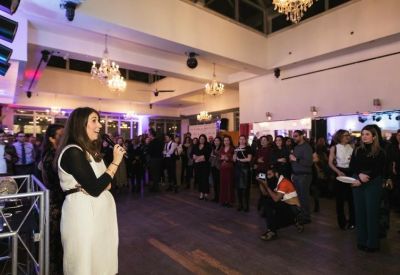 Crowded event space with a speaker addressing an audience.