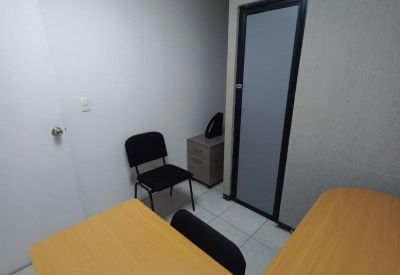 Internal office suite with an L-shaped wooden desk and a black guest chair.