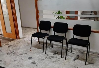Waiting area with three black chairs against a frosted glass partition.