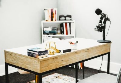 Individual desk setup with podcasting microphones and a white bookshelf.