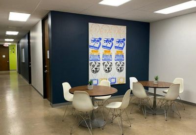 Communal breakout area featuring dark blue accent walls with colorful pop-art and round cafe tables.