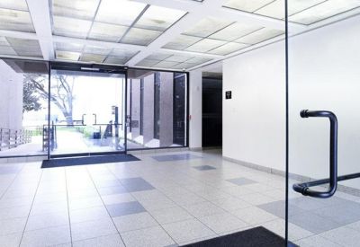Brightly lit modern lobby with floor-to-ceiling glass doors and a geometric ceiling grid.