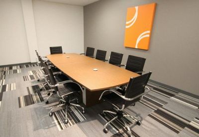 Professional conference room with a large wood-finish table and orange abstract wall art.