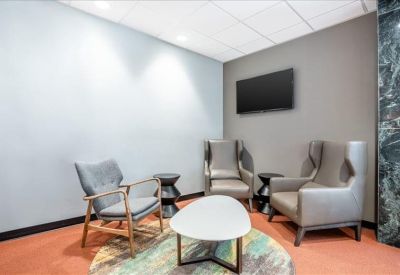 Stylish lounge area with grey armchairs, a white coffee table, and an orange accent floor.