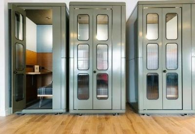 A row of three sleek, olive green soundproof phone booths for private calls.