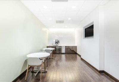 Clean communal kitchen area with white tables, modern cabinetry, and a coffee machine.
