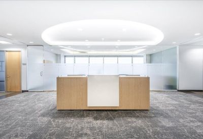 Minimalist reception area featuring a wood-fronted desk and recessed ceiling lighting.