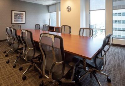 Spacious boardroom featuring a long wooden table and modern mesh chairs overlooking a city view.