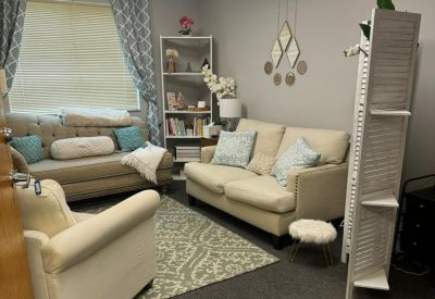 Warm communal lounge area with plush sofas, patterned rug, and decorative wall art.