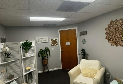 Private office space featuring a white armchair, indoor plants, and soft grey walls.