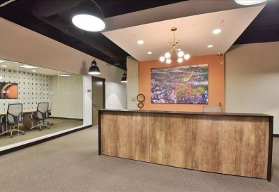 Reception area with a warm wood-fronted desk and a colourful piece of art on the wall.