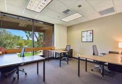 Spacious three-desk office suite with a large window and drop ceiling.