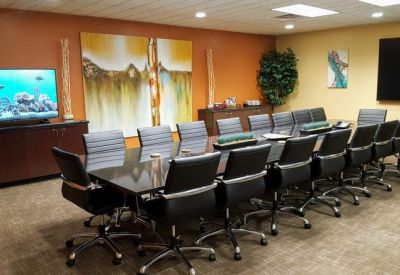 Large professional boardroom with a long dark wood table and black leather chairs.