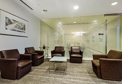 Lounge area with dark leather armchairs and a glass-enclosed meeting room in the background.