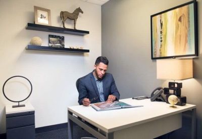 Private office featuring a man at a white desk with decorative wall shelving and horse statuette.