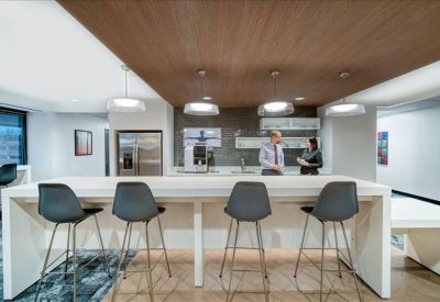 Kitchen and breakout area with high stools and wood-paneled ceiling.