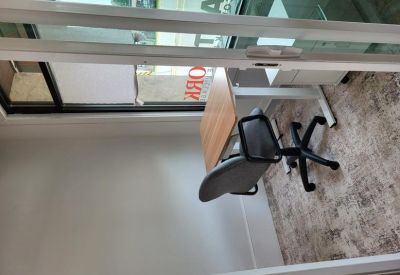 Private workstation with an adjustable chair and wooden desk seen through glass.